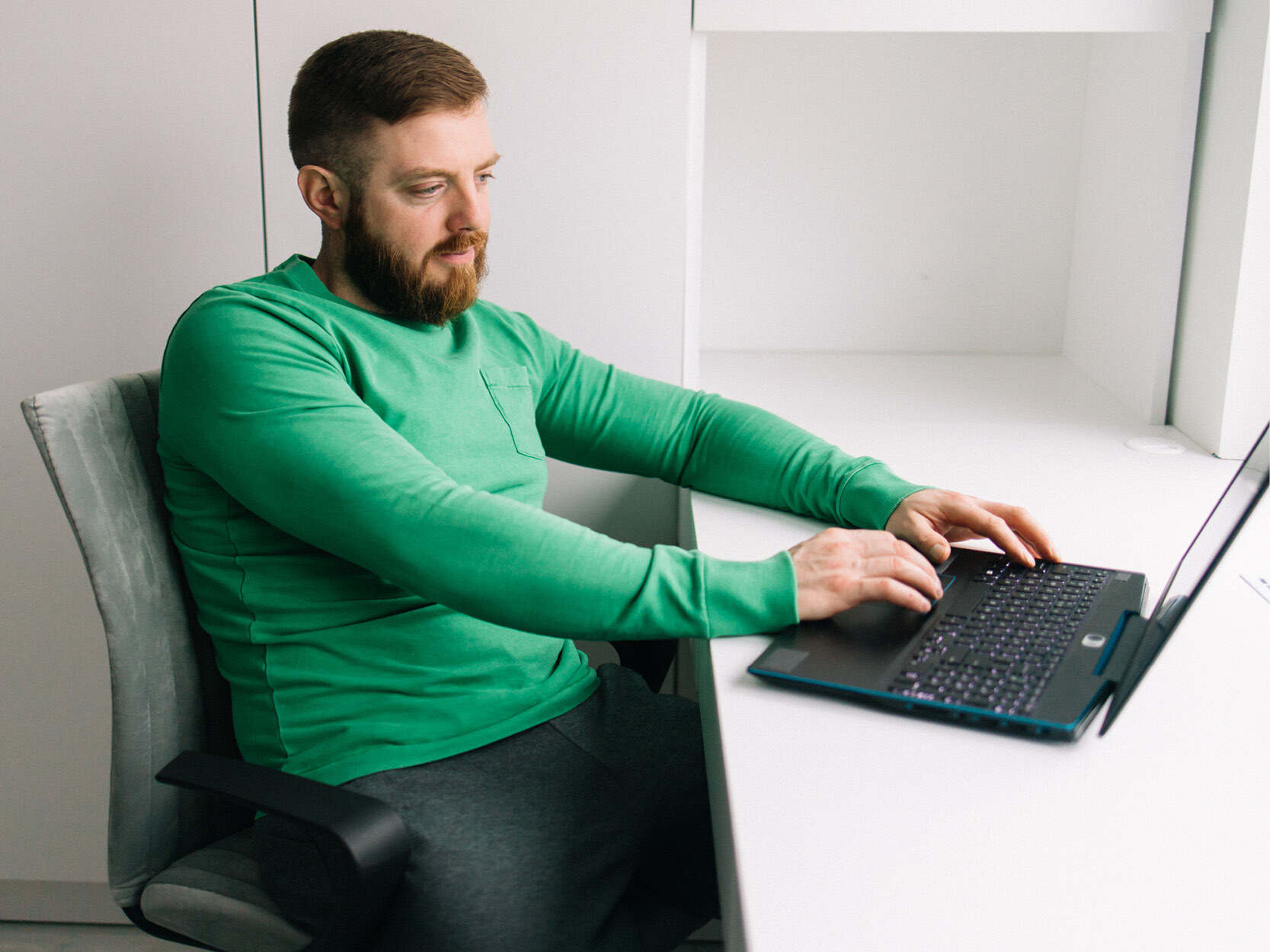 Man in green using computer