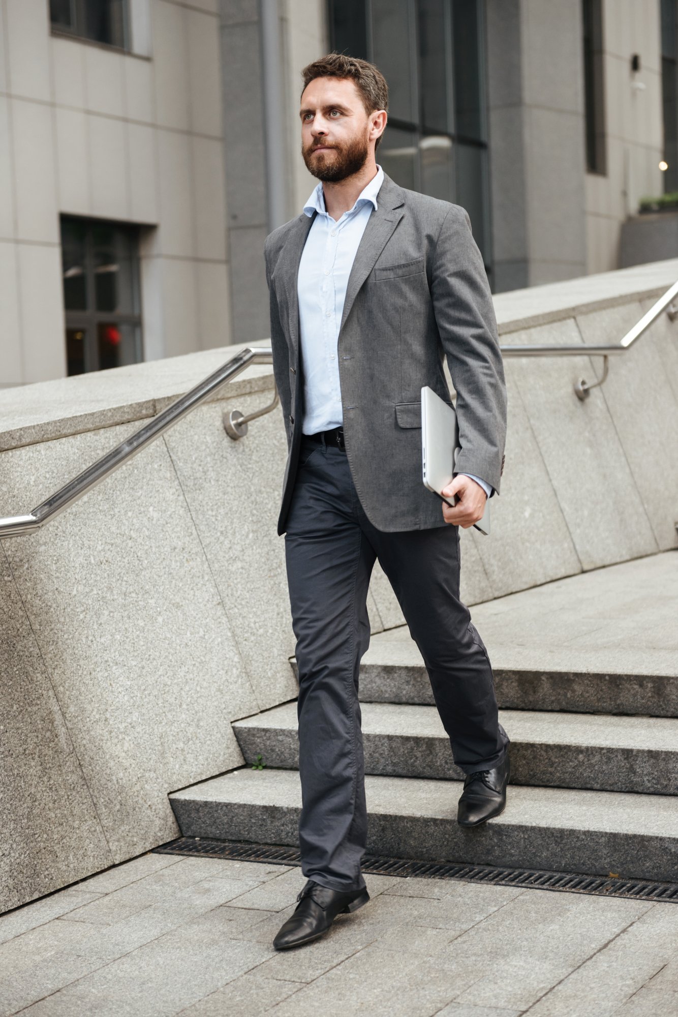 A businessperson walking with a laptop